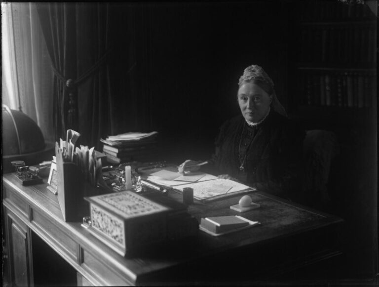 Black and white image of Sophia Jex Blake sat at a desk.